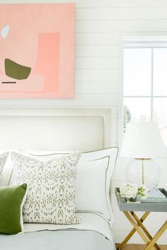 a bed with white sheets and pillows next to a painting on the wall above it