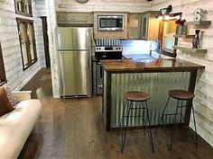 a kitchen with two stools next to an island in the middle of a living room