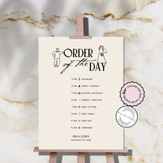 an order of the day sign on a easel with some stickers around it