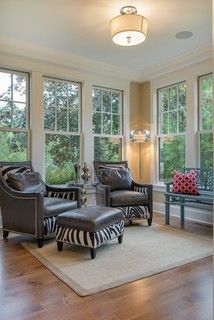 a living room with zebra print furniture and large windows overlooking the trees in the distance