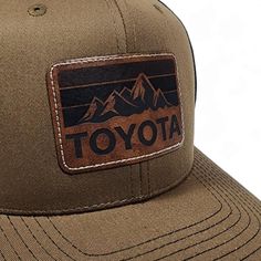 Get nostalgic with our Vintage Style Toyota Laser Engraved Leatherette Patch Trucker Hat featuring the Toyota Mountains logo! Classic design meets modern flair. Elevate your style with comfort. Embrace the road ahead in timeless fashion. Classic Brown Snapback Hat With Flat Bill, Brown Retro Hat For Outdoor, Classic Brown Trucker Hat, Classic Brown Trucker Hat For Outdoor, Retro Brown Baseball Cap For Outdoor, Brown Flat Bill Travel Hat, Brown Trucker Hat With Logo Patch And Flat Brim, Brown Trucker Hat With Flat Brim And Logo Patch, Vintage Brown Trucker Hat For Outdoor