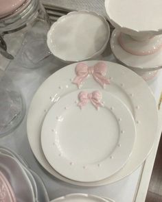 white dishes with pink bows on them are sitting on a table