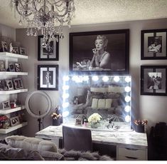 a vanity with lights and pictures on the wall in front of it is lit up by a chandelier