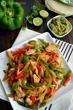 a white plate topped with chicken and veggies next to guacamole