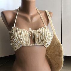 🐚 SEASHELL AND PEARL DETAIL SAND BEIGE CROP BIKINI 🐚 Get ready for an extraordinary beach experience inspired by nature! This handmade crop bikini top is adorned with seashells and pearls, designed in sand beige color. Every detail of this top is meticulously crafted to make you the star of the beach. 🌊 Features and Details: - Handcrafted with natural seashells and pearls. - Sand beige color reflects natural beauty and elegance. - Adjustable straps and ties for a perfect fit. - Long-lasting u Shell Bra Tshirt, Beaded Swimwear For Poolside And Beach Season, Beige Halter Neck Swimwear For Beach Season, Beachy Beige Sleeveless Swimwear, Beige Sleeveless Swimwear For Beach, Beige Sleeveless Beachy Swimwear, Summer Beaded Swimwear For Pool, Beaded Swimwear For Beach Season, Beaded Swimwear For Summer Pool