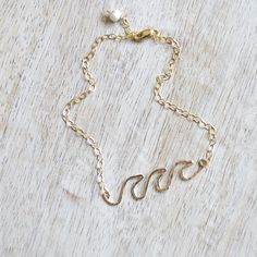 "This beachy triple ocean wave anklet is hand formed from 20g gold filled wire and hammered for a slight glimmer. It's attached to a 2.3mm gold filled flat cable chain and finished with a cute luhauna shell at the end. I make it approximately 1/2\" longer so it dangles slightly and allows for some adjustability. **Please allow for slight variations as each is unique** Approximately 1.75\" wide" Gold Mother Of Pearl Jewelry With Pearl Charm, Brass Dangle Jewelry With Pearl Charm, Gold Brass Jewelry With Pearl Charm, Gold Jewelry With Pearl Charm In Brass, Gold-tone Hammered Dangle Jewelry, Handmade Gold Jewelry With Mother Of Pearl, Handmade Mother Of Pearl Gold Jewelry, Gold Dainty Mother Of Pearl Jewelry, White Hammered Dangle Jewelry