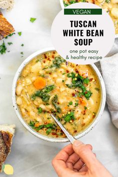 vegan tuscan white bean soup in a bowl with a hand holding a spoon