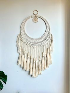 a white wall hanging with tassels and a circular ring on the top of it