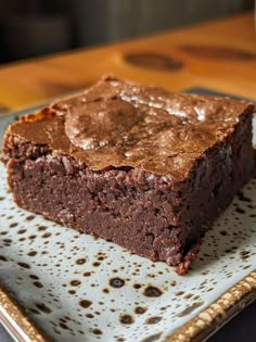 a square brownie sitting on top of a plate next to a glass of milk