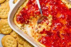 a casserole dish filled with cheese and sauce next to crackers