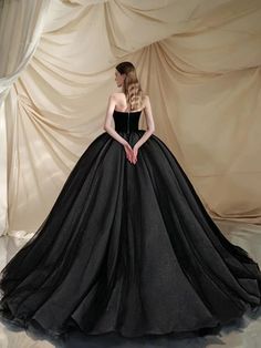 a woman in a black ball gown is posing for the camera with her hands on her hips