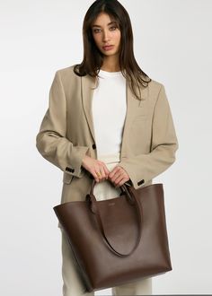 It’s time for a bag designed just for you. Every detail—from the quality of vegetable-tanned leather to the interior pockets to the silhouette—the Mila Tote was designed with the working professional in mind. Take her from the office with enough space for your 13" laptop, planner, and other everyday essentials to an after-work shopping date. By tethering the sides, you basically have two designs in one. Just like you, the Mila Tote is for the boss woman who can do it all! Office-friendly Tan Tote Bag, Sleek Leather Tote Shoulder Bag, Sleek Soft Leather Tote Bag, Black Leather-handled Tote Laptop Bag, Dark Tan Leather-lined Tote Bag, Boss Woman, Stroller Hooks, Working Professional, Shopper Tote