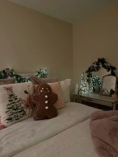 a bed with two pillows and a teddy bear on top of it in front of a christmas tree