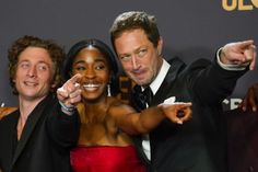 two men and a woman pointing at the camera