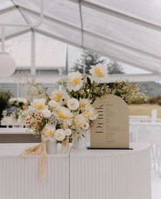 white and yellow flowers in vases on top of a table at a wedding reception