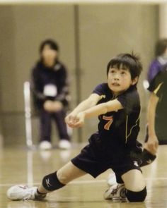 a young boy is playing with a frisbee in an indoor court while other people watch