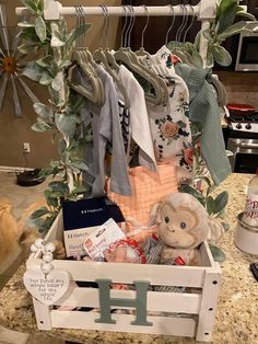 a wooden crate filled with clothes and other items on a kitchen counter next to a cat