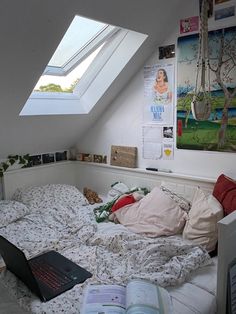 an open laptop computer sitting on top of a bed in a room with slanted ceilings