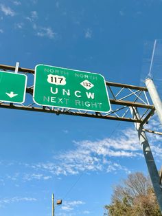 two green street signs mounted to the side of a metal pole under a blue sky