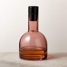 a brown glass bottle sitting on top of a white counter next to a black lid