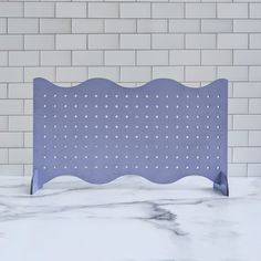 a white and blue tile wall next to a purple metal rack with holes on it