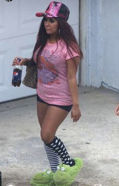 a woman in pink shirt and black shorts on skateboard