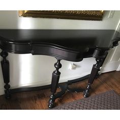 a black console table sitting on top of a hard wood floor next to a door