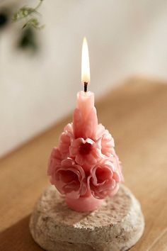 a small pink candle sitting on top of a rock