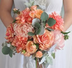 a bridal holding a bouquet of peach colored flowers and greenery in her hands