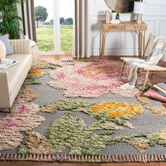 a living room filled with furniture and a rug on top of a hard wood floor