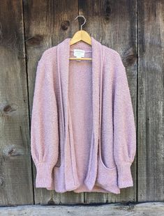 Chunky mauve knit cardigan sweater, 1990s vintage. A cute tufted oversize sweater, perfect for tossing on over a slip dress or jeans... Features a chunky light purple/pink acrylic knit, stylish rolled collar that turns into structural pockets at the base, open front for an easy fit, chic bishop sleeves, an elongated over-the-hips hemline, and lots of casual retro glamour... Warm, comfy, and unique...the perfect go-to layer for a chilly evening....;) Brand : Sideffects Made in Hong Kong in 1994 100% acrylic Labeled size L But the open front and intentionally loose fit allows for plenty of leeway All measurements taken with garment pulled closed and lying flat, double where necessary roughly 19 inches shoulder seam to shoulder seam roughly 21 inches pit to pit hips & hem loose roughly 35 inc Cozy Pink Sweater With Pockets, Cozy Purple Soft Knit Outerwear, Pink Oversized Bohemian Cardigan, Retro Glamour, Oversize Pullover, Oversize Sweater, Pull Oversize, Oversized Sweater Cardigan, Rolled Collar