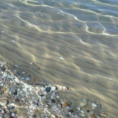 some rocks and sand on the beach by the water