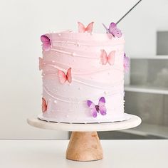 a cake with pink frosting and butterflies on it