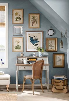 a home office with blue walls and pictures on the wall, along with a wicker chair