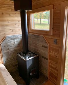 a wood burning stove in the corner of a room with wooden walls and flooring