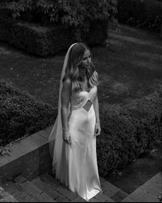 a woman in a wedding dress is standing outside