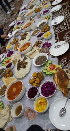 a long table filled with lots of different types of food on top of plates and bowls