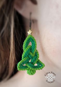 a woman wearing green crochet earrings with a star on the top of it