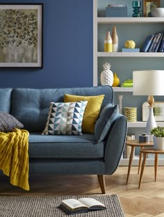 a living room with blue walls and yellow throw pillows on the couch in front of it