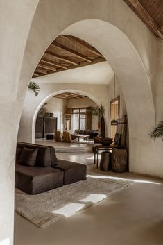 a living room filled with furniture and a large archway leading to the dining room area