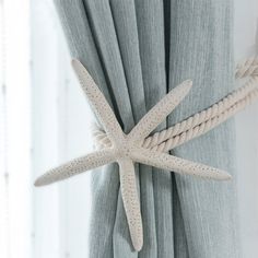 a white starfish hanging on the side of a curtain