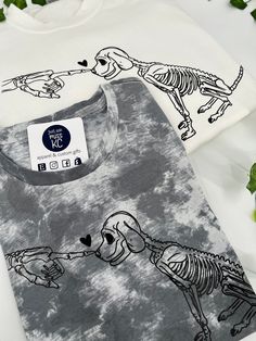 two t - shirts with dogs and bones on them, one is white and the other is gray