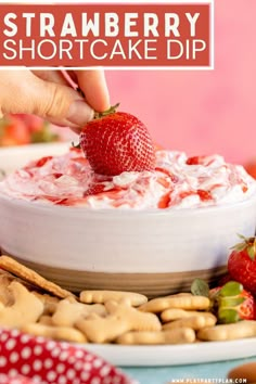 a strawberry shortcake dip in a white bowl surrounded by crackers and strawberries