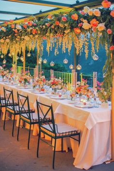 a long table set up with flowers and candles for an outdoor dinner or party event