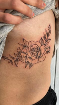 a woman's stomach with a rose tattoo on it