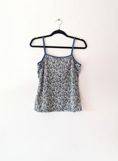 a vintage blue and white floral plisse camisole top ✿ IMPORTANT INFORMATION: * excellent vintage condition * material: 100% polyester * size: medium - please check exact measurements below (they're there for your benefit!) * garment care: machine washable ✿ MEASUREMENTS (taken while item is lying flat, some measurements will need to be doubled): * armpit to armpit: 16" (41cm) * length (top of strap to bottom hem): 22" (56cm) ✿ free UK shipping on orders over £100 with code STRAWBERRY free intern Floral Print Camisole Tops For Daywear, Blue Floral Print Camisole For Spring, Vintage Camisole Tank Top For Spring, Vintage Sleeveless Camisole For Summer, Cotton Camisole Tops With Floral Print, Blue Tank Top For Spring Daywear, Blue Tank Top For Daywear In Spring, Blue Spaghetti Strap Vest Top, Vintage Camisole Tank Top For Summer