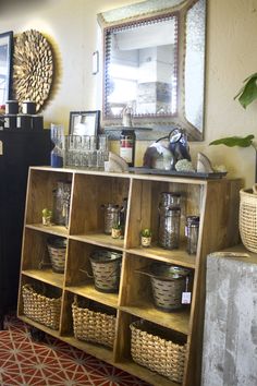 a shelf with baskets and other items on it next to a mirror in a room