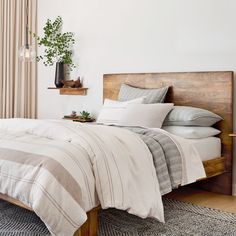 a bed with white sheets and pillows in a bedroom next to a wooden headboard