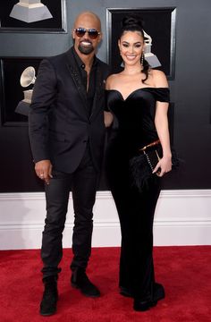 a man and woman standing on top of a red carpet