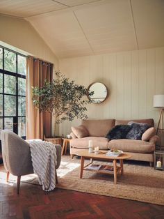 a living room filled with furniture next to a large window and a wooden floor covered in rugs